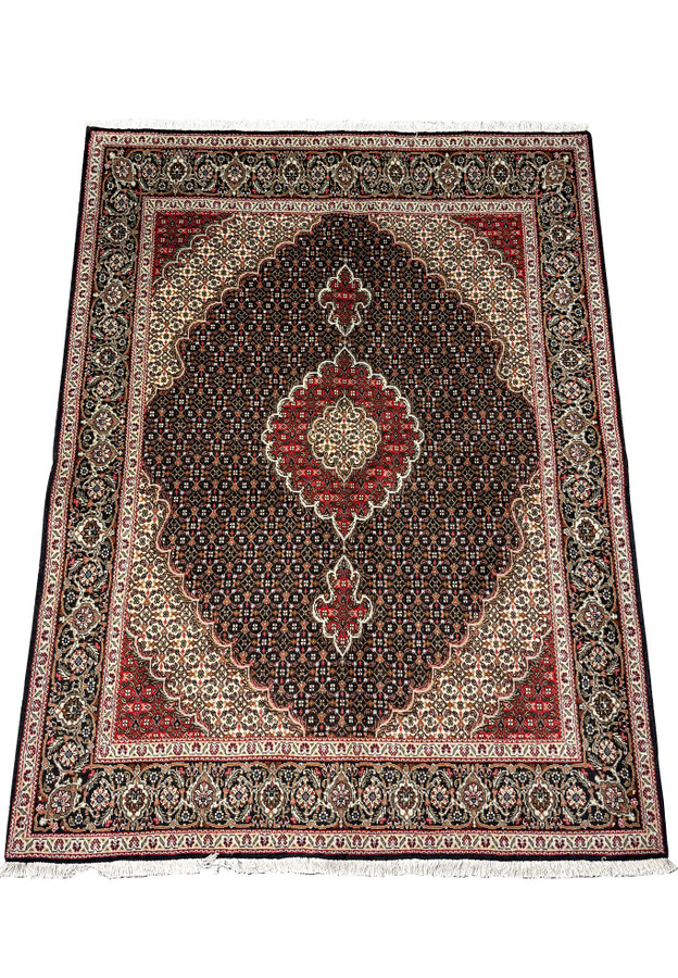 Overhead view of a Persian Tabriz Mahi rug, featuring a detailed Mahi design in dark brown, cream, and red, with a navy blue and ivory border.