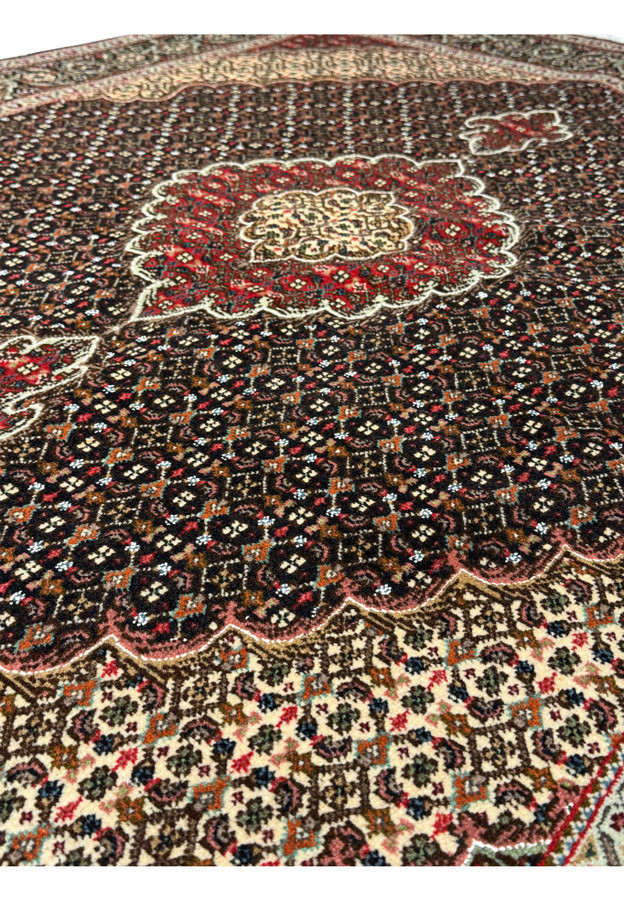 Lush texture and intricate pattern of a Persian Tabriz Mahi rug with a cream and red medallion set against a dark brown field, bordered in navy blue and ivory.