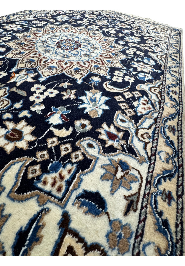 Angle shot of the Persian Nain rug, emphasizing the luxurious texture and elaborate border design