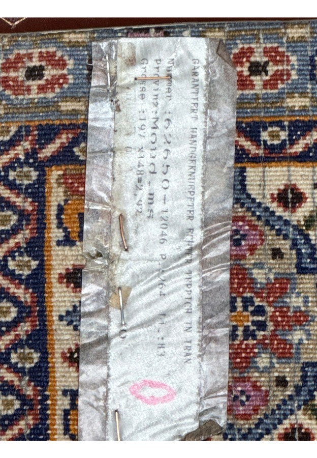 Detail of a label on the Persian Moud Rug indicating its origins, size, and authenticity.