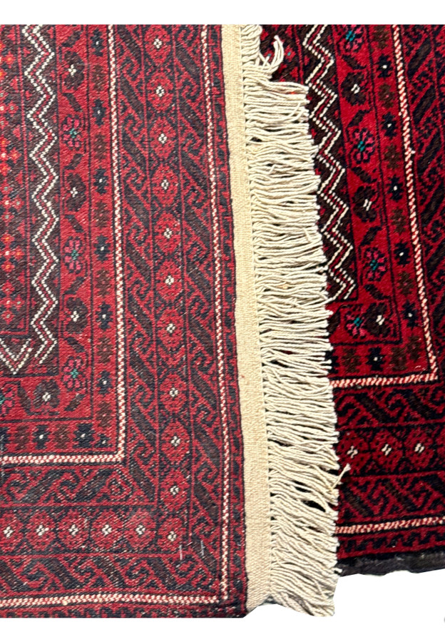 Edge view of a rolled Persian Baluch rug, accentuating the tight weave and thickness of the handmade carpet