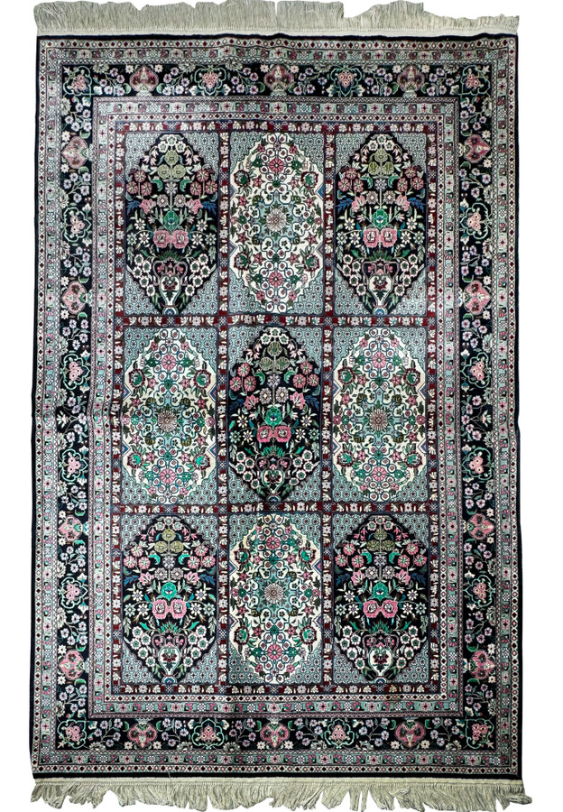 Close-up of the intricate floral and geometric patterns on a Persian Qum silk rug with shimmering silk threads