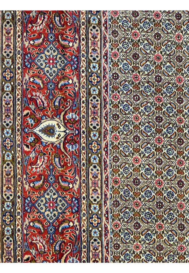 Detailed shot of the Persian Moud Rug's border featuring ornate floral designs and prominent medallions against a deep red backdrop