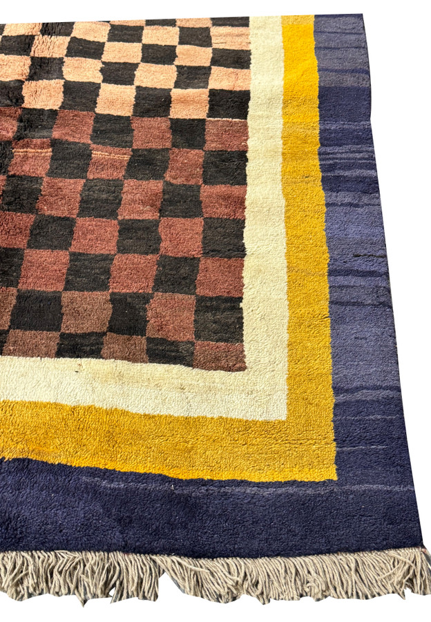 A detailed perspective of the Nepal rug's corner, showing the interplay of indigo, golden yellow, and checkerboard patterns with fringe detail.