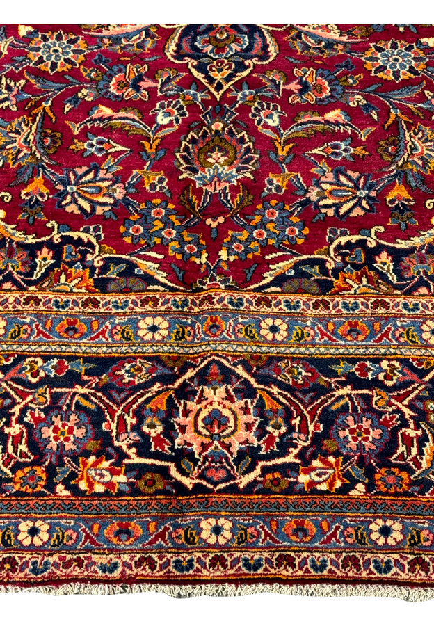 Corner detail of the Persian Kashan rug, where the opulent border meets the vibrant, patterned field.