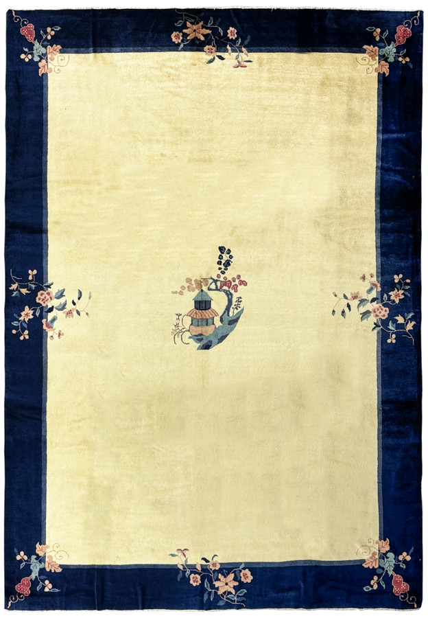 A 10 x 14 vintage Art Deco rug with a navy blue border and a central beige field displaying a stylized vase motif and corner floral designs, in pristine condition