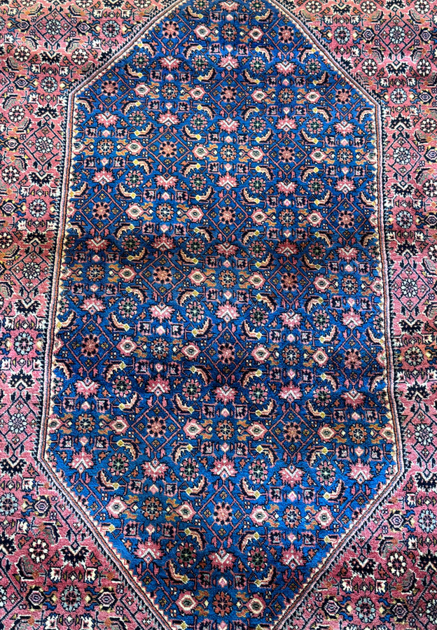 A Persian Bijar carpet of grand proportions, featuring a central medallion filled with a mosaic of symbols, framed by an intricate border, exemplifying the timeless beauty and precision of Persian rug-making