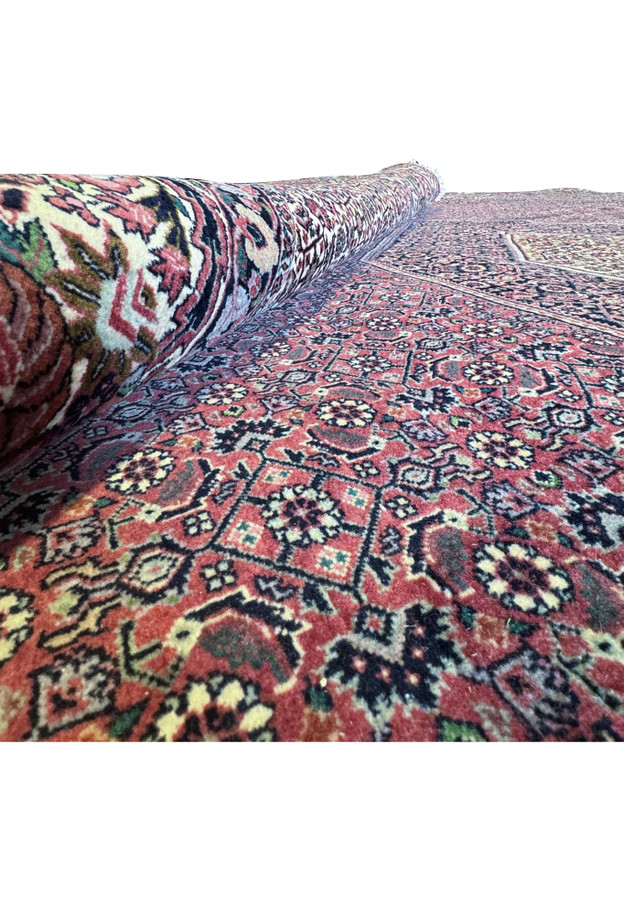The rug is carefully rolled up, allowing a magnified examination of the weave quality and the plushness of its wool pile, showcasing the extraordinary craftsmanship.