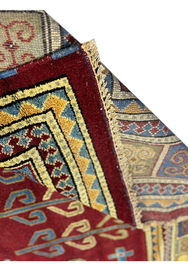 A close view of the corner of the rug, showcasing the precision of the patterns where the borders meet, with detailed motifs in blue, red, yellow, and cream.