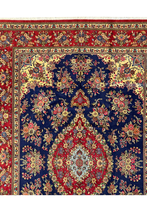 Close view focusing on the side border of the Persian Qum Kork rug, showing detailed floral and vine patterns in a vivid array of reds, creams, and gold