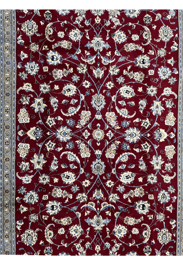 Close-up of the central pattern of the Persian Nain 9La rug, highlighting the detailed floral designs in cream and blue on a rich red background