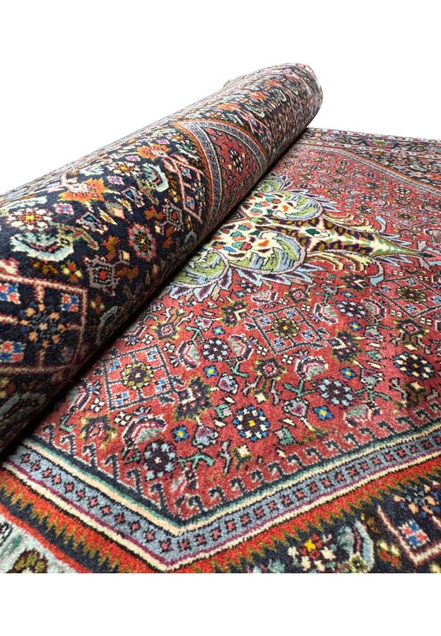 Partially rolled Persian Bidjar rug showing intricate design: This image shows the 4x6 Persian Bidjar rug partially rolled, providing a view of the detailed design and patterns on both the field and border, highlighting the rug's craftsmanship.