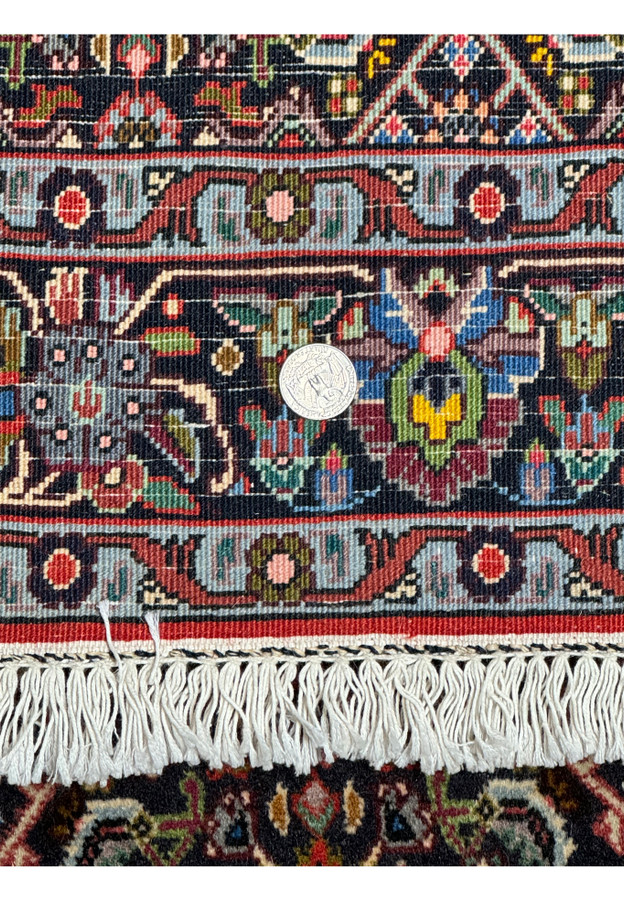 Close-up of the Persian Bidjar rug's weave with a coin for scale: A detailed close-up of the rug's weave, with a coin placed for scale, showcasing the tightness of the weave and the fine craftsmanship characteristic of high-quality Bidjar rugs.