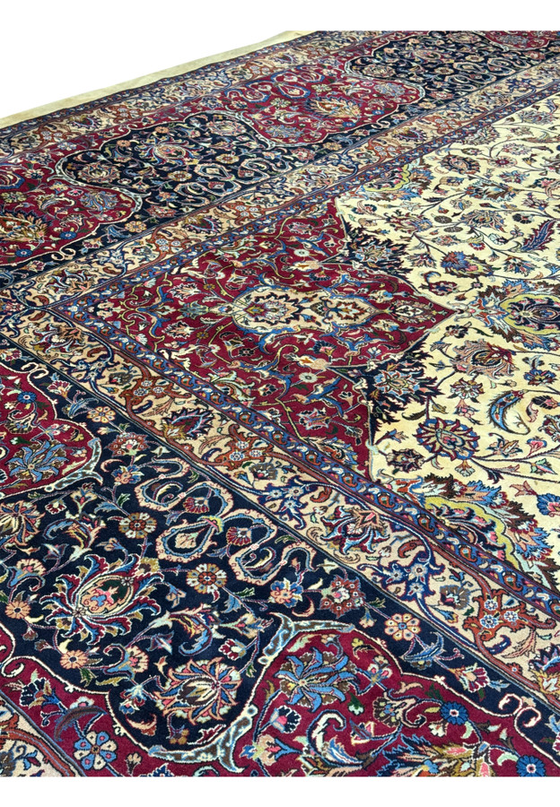 Close-up view of detailed floral motifs and intricate patterns on a Persian Mashad rug, showcasing vibrant colors such as red, blue, ivory, and gold, with meticulous craftsmanship and traditional Persian design elements.