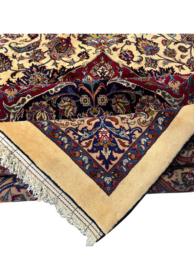 Close-up view of detailed floral motifs and intricate patterns on a Persian Mashad rug, showcasing vibrant colors such as red, blue, ivory, and gold, with meticulous craftsmanship and traditional Persian design elements