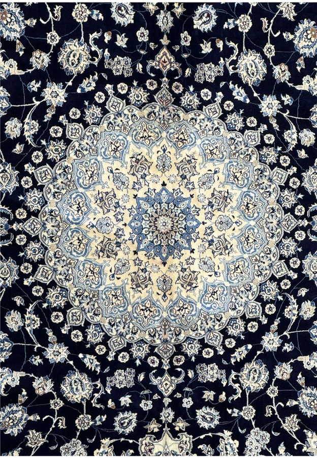 Detailed view of the central medallion on a 13x19 Nain Persian rug, featuring intricate floral patterns in navy blue, ivory, and light blue, highlighting the rug's fine craftsmanship and traditional design