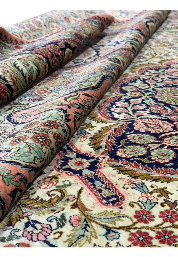 Rolled view of a 8x10 Persian Tabriz 100% silk rug showcasing its softness and intricate design