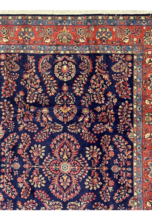 Upper corner of Persian Sarough rug with floral border and signature detail.