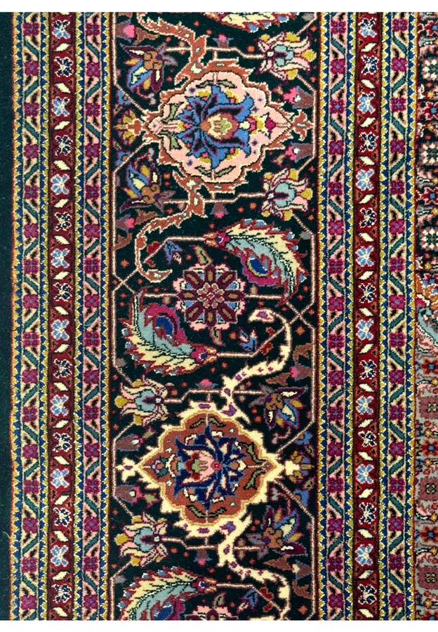 Close-up of the floral border design in the Tabriz rug with repeating vine and flower patterns.