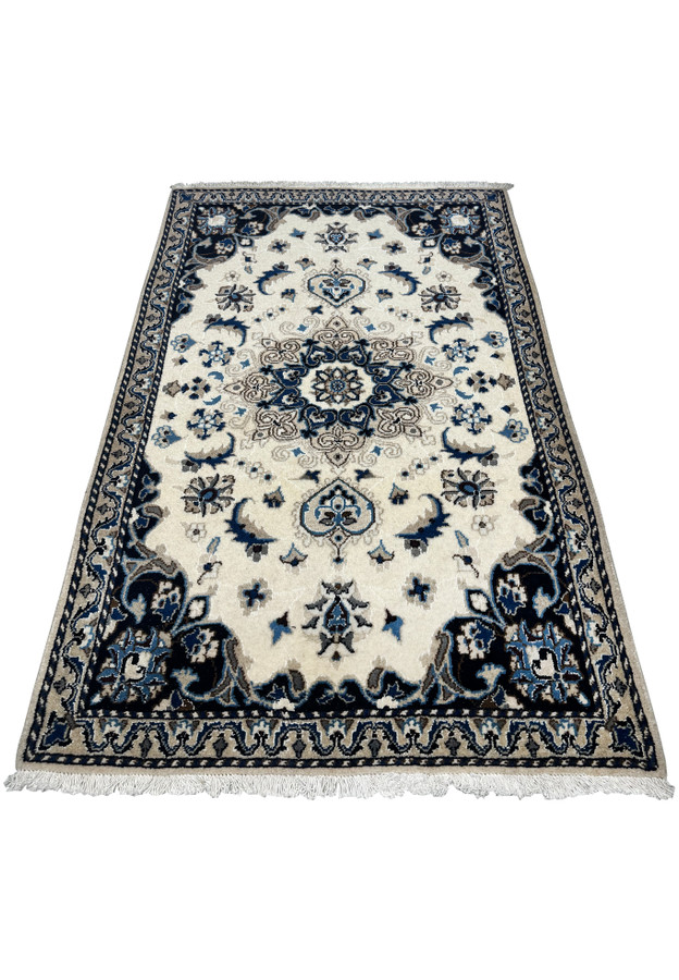 Nain Persian rug laid flat, displaying the traditional medallion and floral patterns with intricate borders in a neutral color palette.