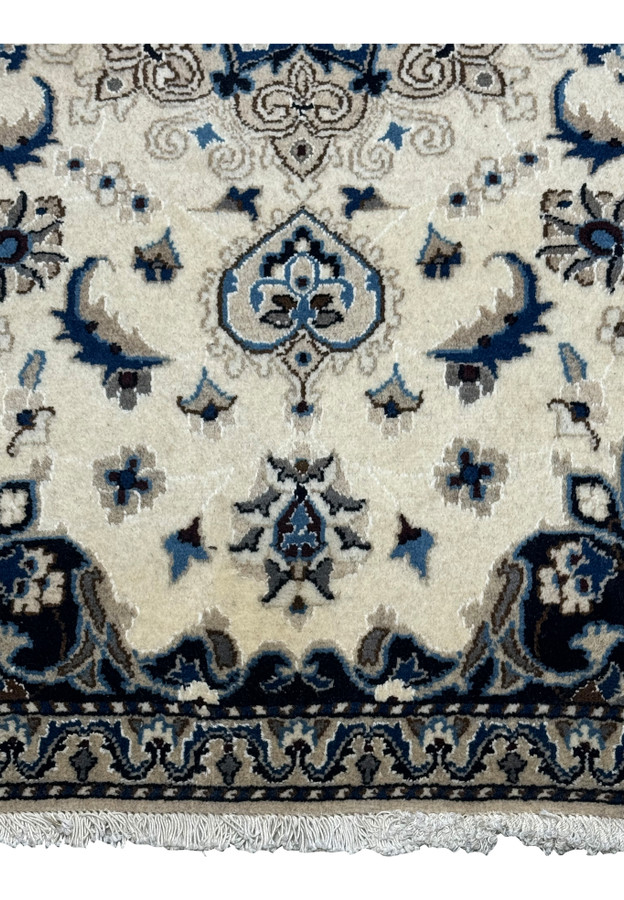 Detailed view of the lower portion of the Nain Persian rug, showing floral motifs and fine wool texture in ivory and navy.