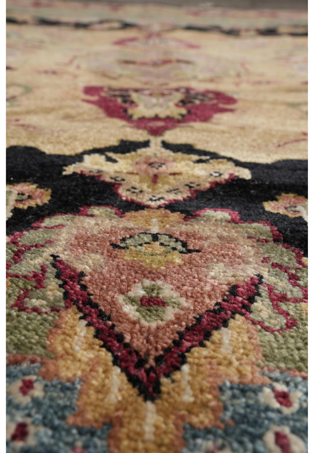 Close-up of Oushak rug texture featuring floral medallion in burgundy, black, gold, and olive with visible wool pile.
