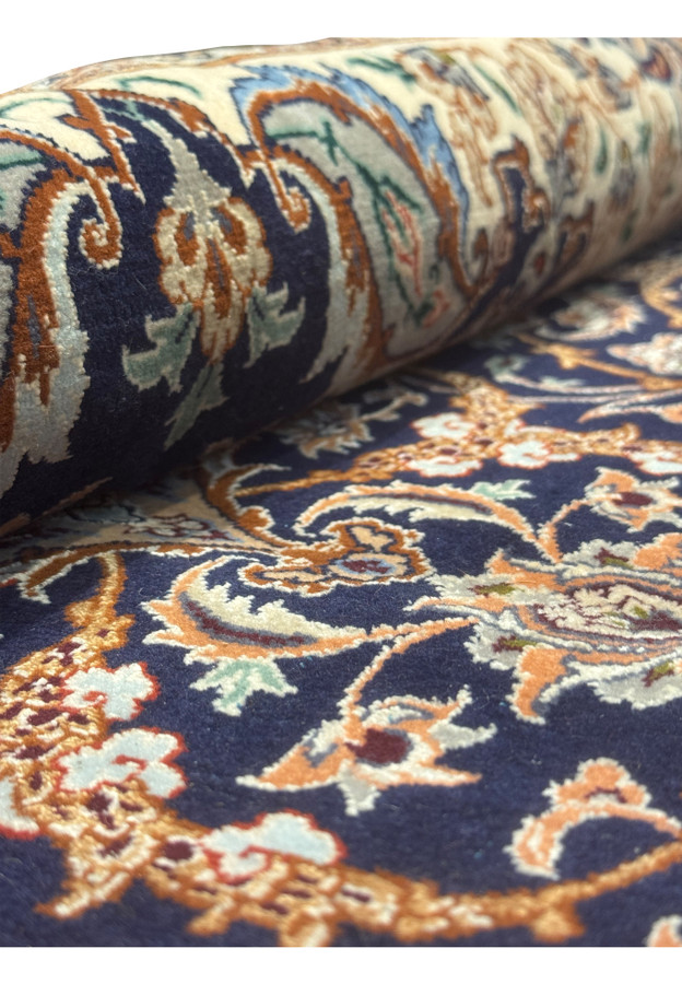 Side angle of Persian Isfahan rug partially rolled, highlighting texture and fine silk and wool weave