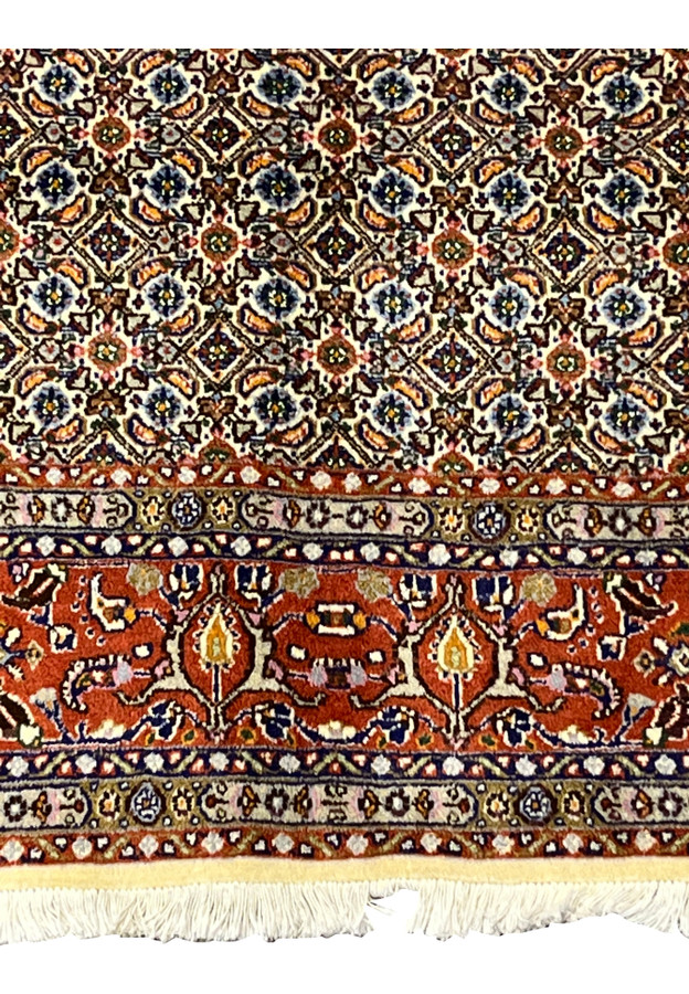 Bottom edge with ivory fringes and rust red border adorned with flowers.