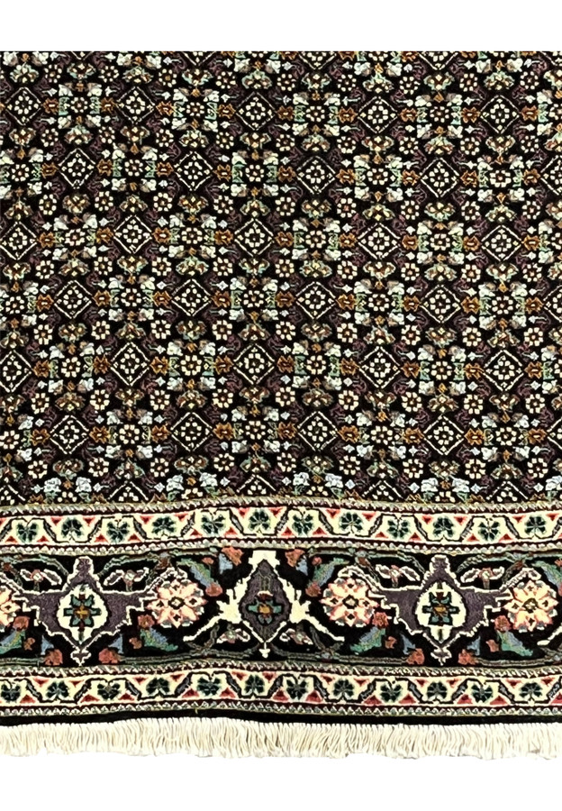 Lower edge of Persian Tabriz Mahi rug with ivory floral border and fringes