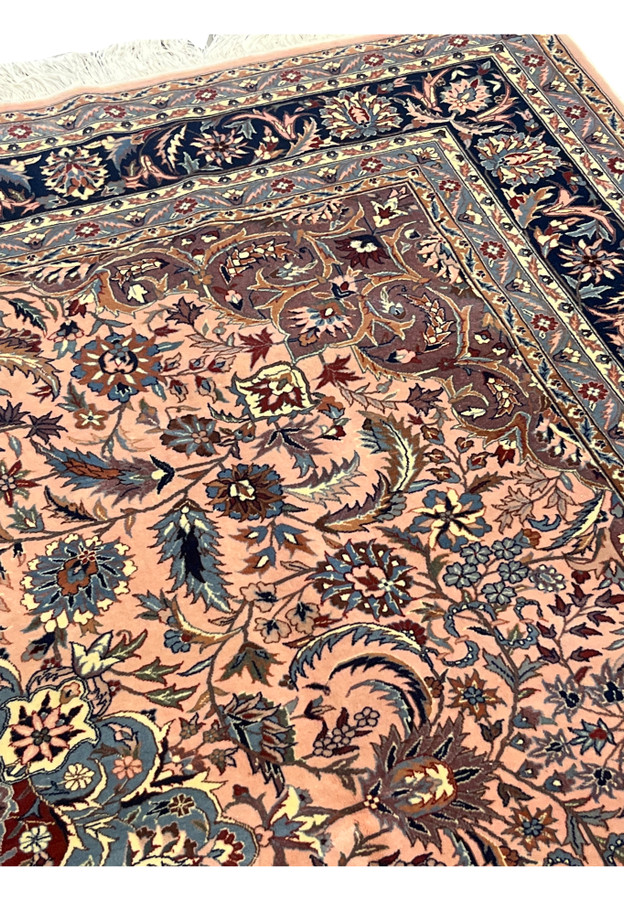 Upper edge of Persian Tabriz rug showing ivory fringes and navy floral border