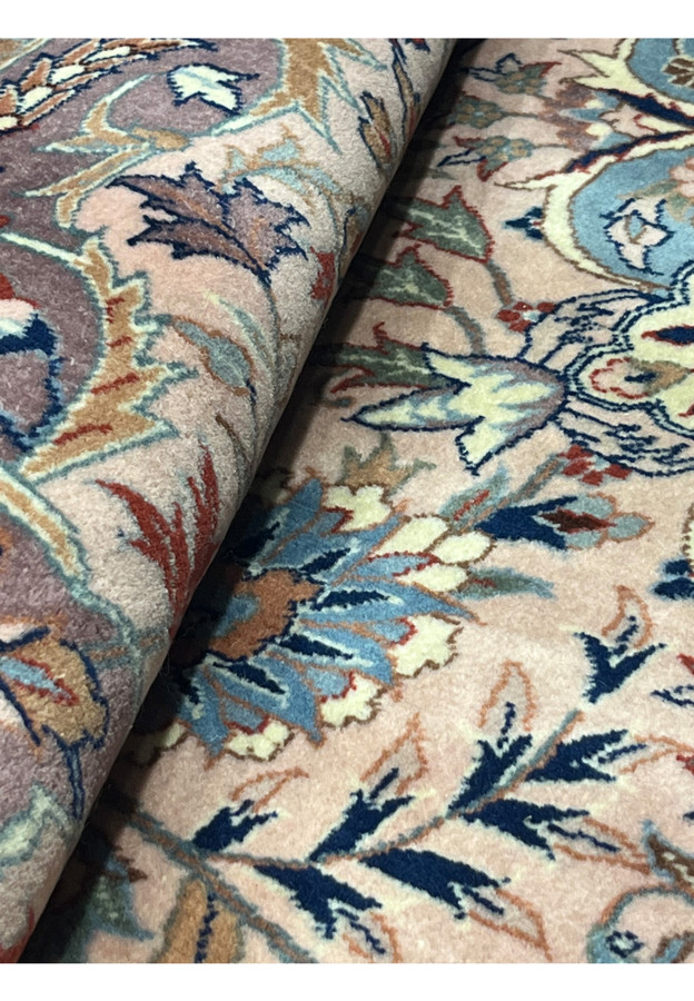 Rolled view of Persian Tabriz rug displaying pile softness and detailed floral designs