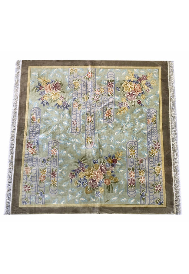 Top-down image of the Oriental Art Deco wool rug highlighting the symmetrical arrangement of pastel floral motifs and scroll lattice patterns on a muted green and blue field with deep taupe borders.