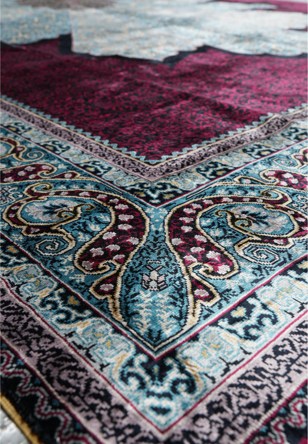 Angled perspective of silk oriental rug highlighting reflective sheen and intricate border design