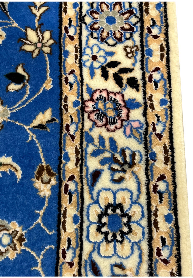 Floral border section of Persian Nain 6LA Runner, showcasing ivory ground and blue silk outlines