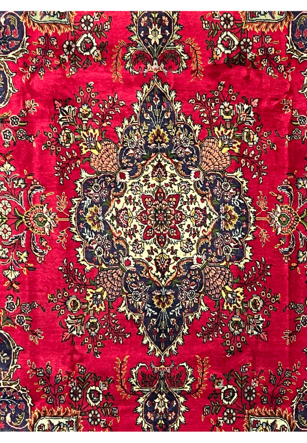 Close-up of central ivory medallion with floral motifs on red background of Persian Tabriz wool rug