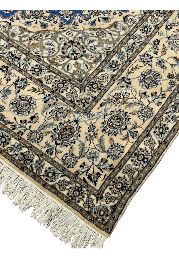 Close-up of rug edge showing ivory border with intricate floral vines and beige outlines