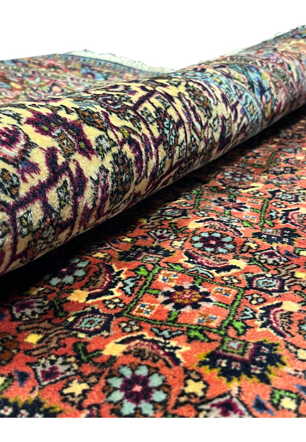 Rolled view of the Persian Bijar Iron Rug showing thick wool pile, ivory floral medallion, and dense field pattern.
