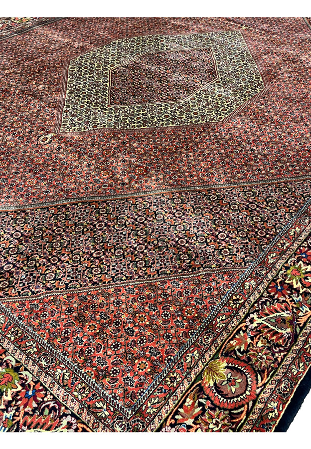 Angled close-up of the medallion and brick red field, highlighting dense Bijar floral and Herati motifs.