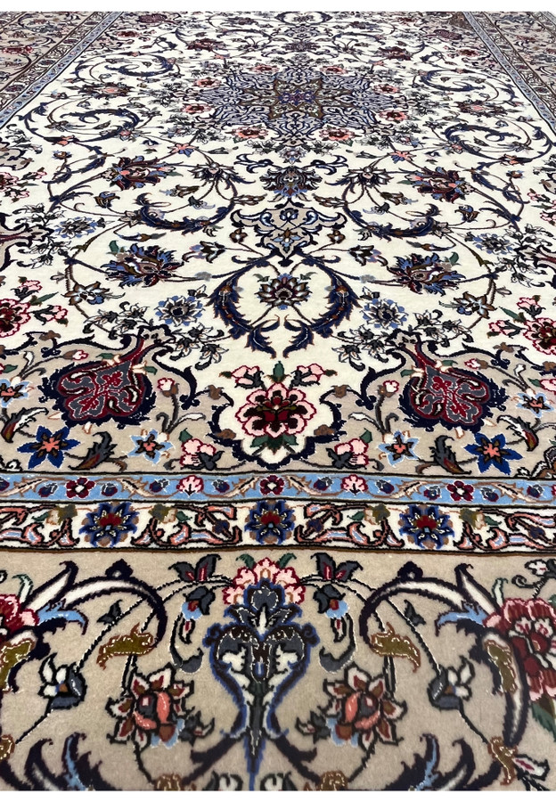 Field close-up showing scrolling navy vines, pink blossoms, and fine silk accents on ivory wool.