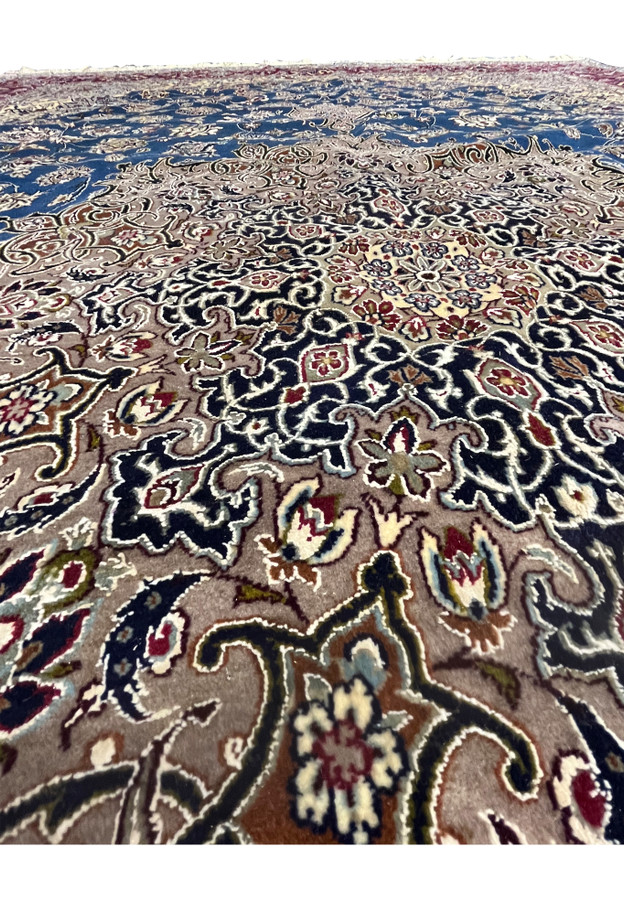 Low-angle detail view of the Persian Isfahan rug showing the floral motifs, navy and beige medallion work, and wool-silk texture across the field.