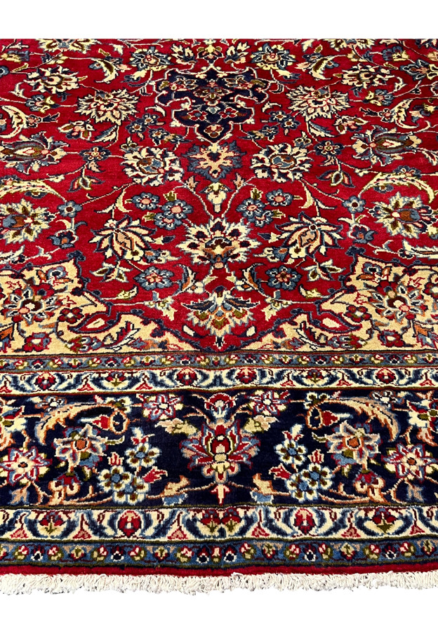 Close-up of Persian Isfahan rug border showing navy floral bands, vines, and small decorative motifs
