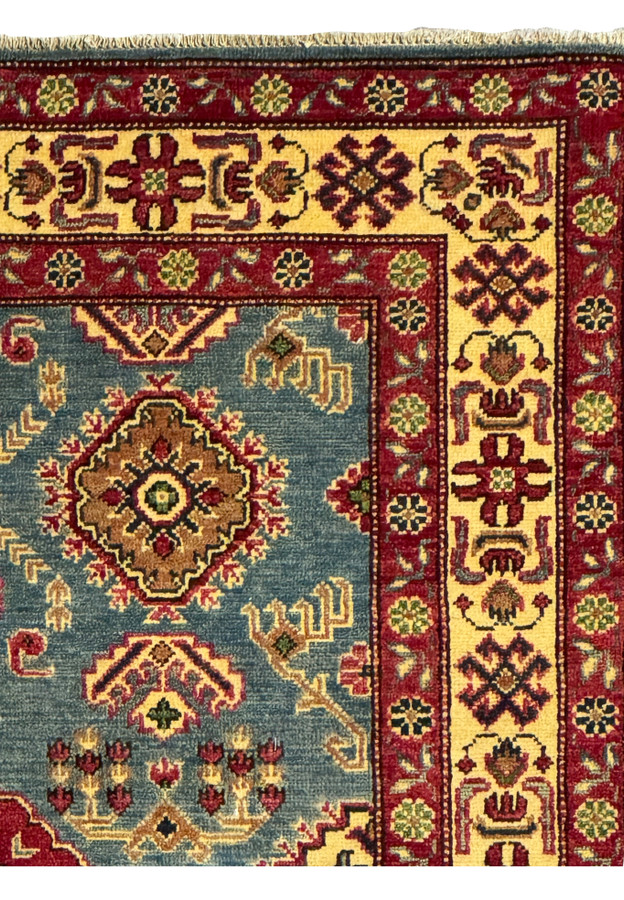 Closeup of the Kazak runner’s border with gold, red, and ivory geometric designs.