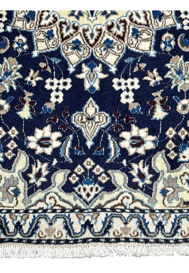 Lower field detail showing ivory floral motifs on deep royal navy Persian Nain rug
