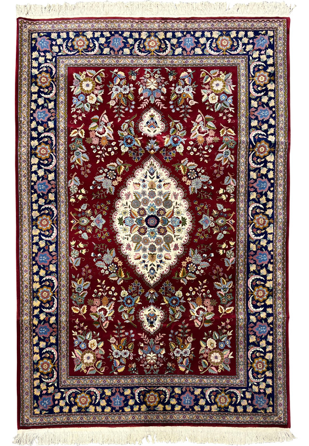 Full view of Persian Isfahan wool and silk rug with burgundy field, ivory medallion, and navy floral border