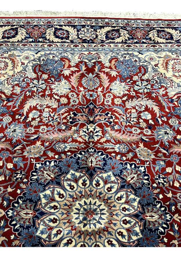 Upper field closeup of Persian Tabriz rug showing burgundy floral pattern beneath the navy top border and ivory framing
