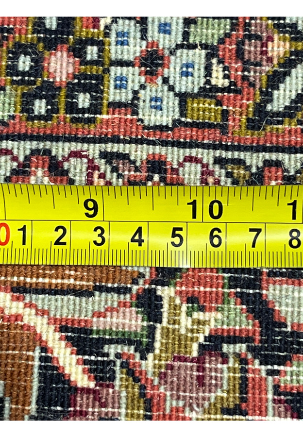 Backside view of a Persian Bijar iron rug with ruler showing tight knot density and precise hand knotted structure