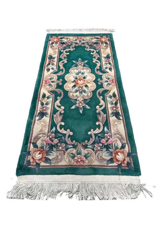 Laid flat Aubusson Art Deco rug showing emerald green background, sculpted floral scrolls, ivory framing, and balanced decorative layout