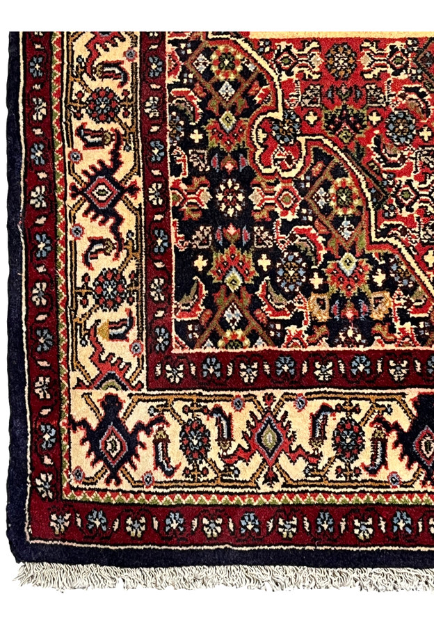 Border detail of a Persian Bijar rug showing repeating floral motifs, ivory ground, navy outlines, and precise hand-knotted craftsmanship
