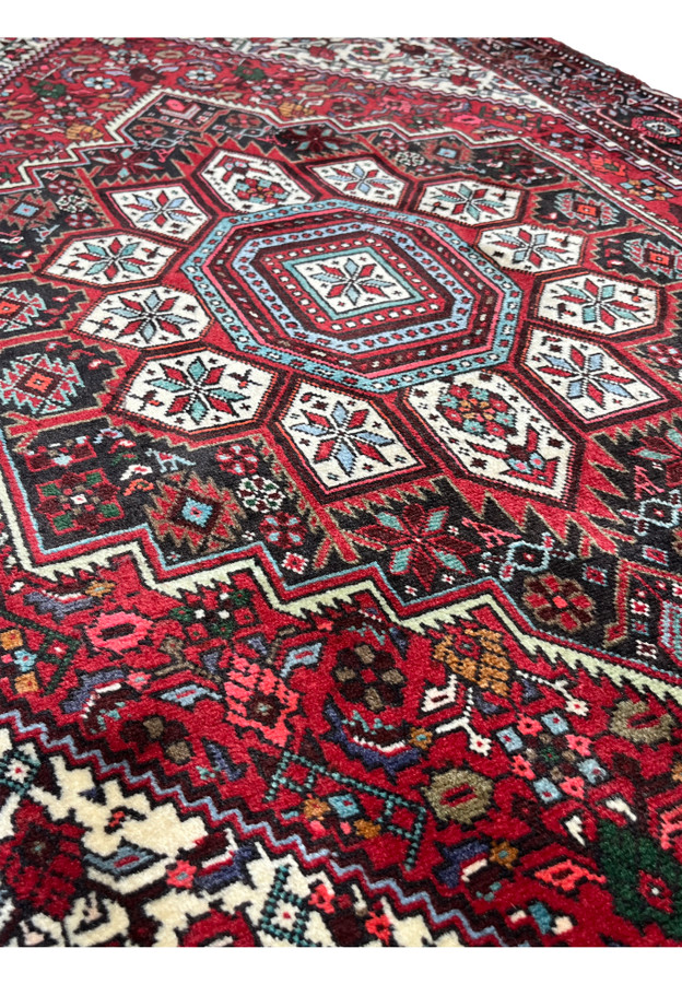 Close-up of octagonal medallion and surrounding tribal motifs on a 3'4 x 5'5 Persian Gholtogh rug, showing saturated red field, ivory accents, turquoise highlights, and dense hand-knotted wool texture