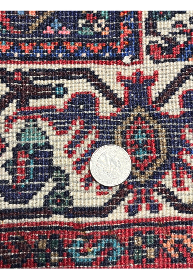 Backside detail of Persian Gholtogh rug with coin for scale, showing fine knot density, durable wool weave, and precise tribal craftsmanship